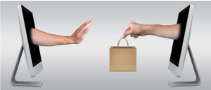 A pair of hands passing a shopping bag through two different computer monitors.